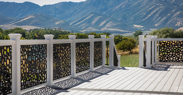 Ornament deck railing with black patterned panels and white posts enhancing outdoor deck design against mountain backdrop Ornament deck railing with black patterned panels and white posts enhancing outdoor deck design against mountain backdrop