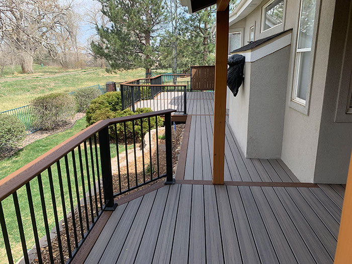 Composite brown and black deck railing design with a spacious outdoor deck overlooking a green backyard area. Composite brown and black deck railing design with a spacious outdoor deck overlooking a green backyard area.