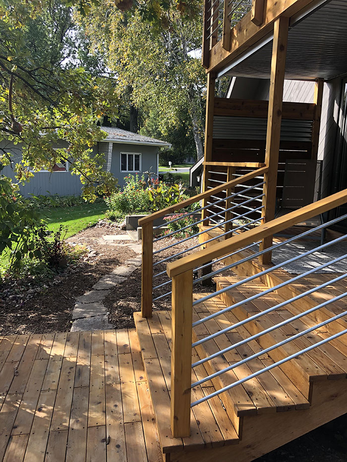 Wooden deck railing with metal horizontal bars in different colors enhancing modern deck railing ideas outdoors. Wooden deck railing with metal horizontal bars in different colors enhancing modern deck railing ideas outdoors.