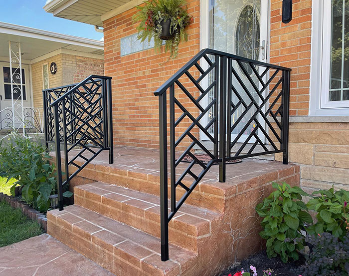 Black patterned metal deck railing with geometric design installed on brick steps enhancing exterior appearance. Black patterned metal deck railing with geometric design installed on brick steps enhancing exterior appearance.