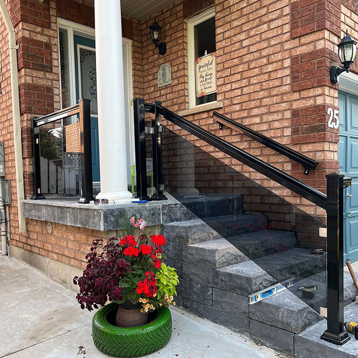 Tinted glass single-panel deck railing with black metal posts enhancing modern exterior deck design. Tinted glass single-panel deck railing with black metal posts enhancing modern exterior deck design.