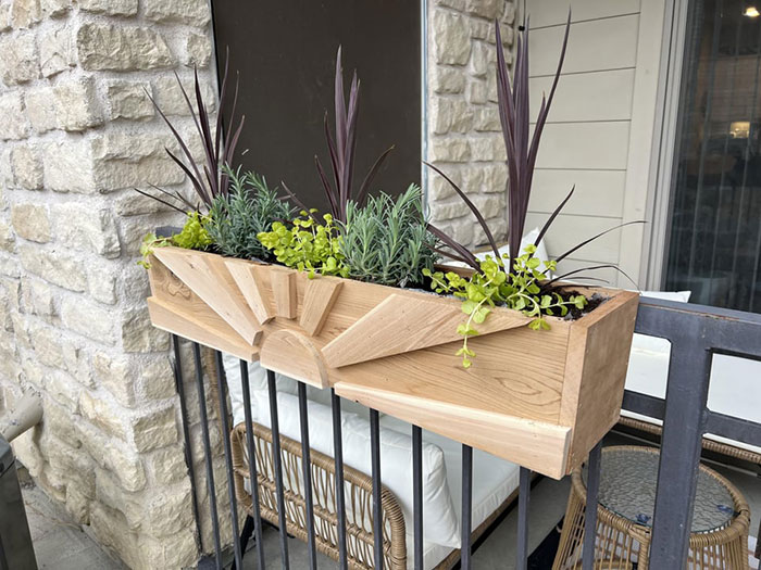 Flower pots with greenery in a decorative wooden planter on black metal deck railing for exterior design ideas Flower pots with greenery in a decorative wooden planter on black metal deck railing for exterior design ideas