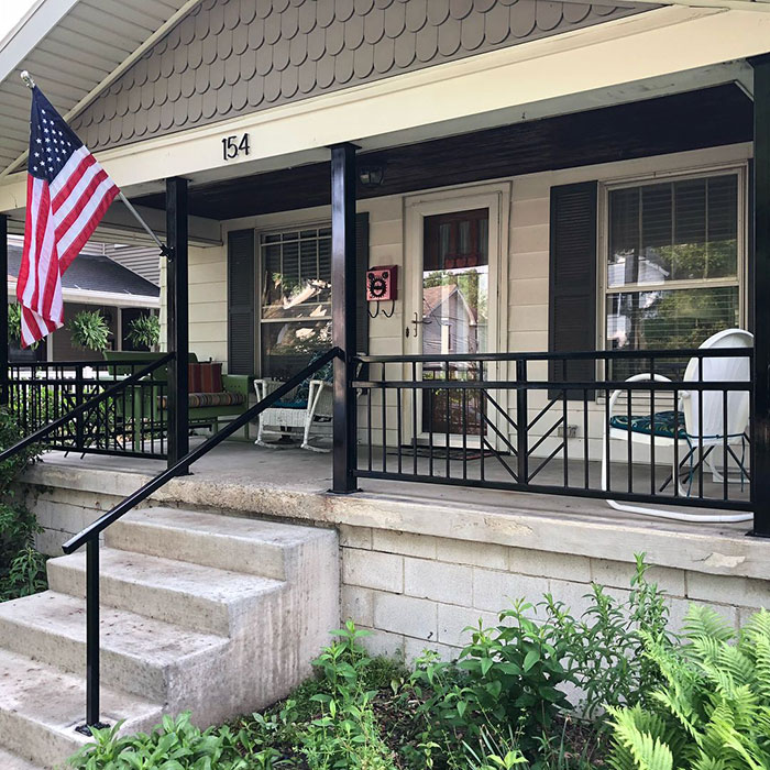 Black arrowhead deck railing design enhancing a house porch exterior with steps and nearby greenery. Black arrowhead deck railing design enhancing a house porch exterior with steps and nearby greenery.
