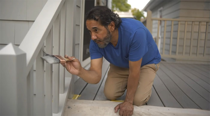 Man carefully painting white deck railing, enhancing outdoor space with creative deck railing ideas and designs. Man carefully painting white deck railing, enhancing outdoor space with creative deck railing ideas and designs.