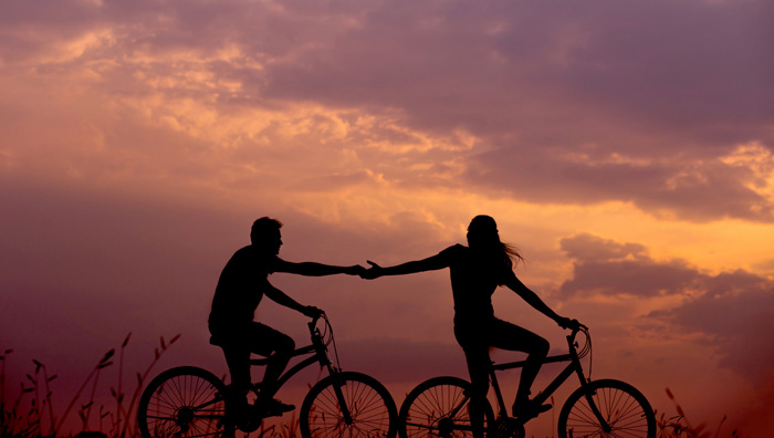 Woman and man on a bike reaching hands to each other 