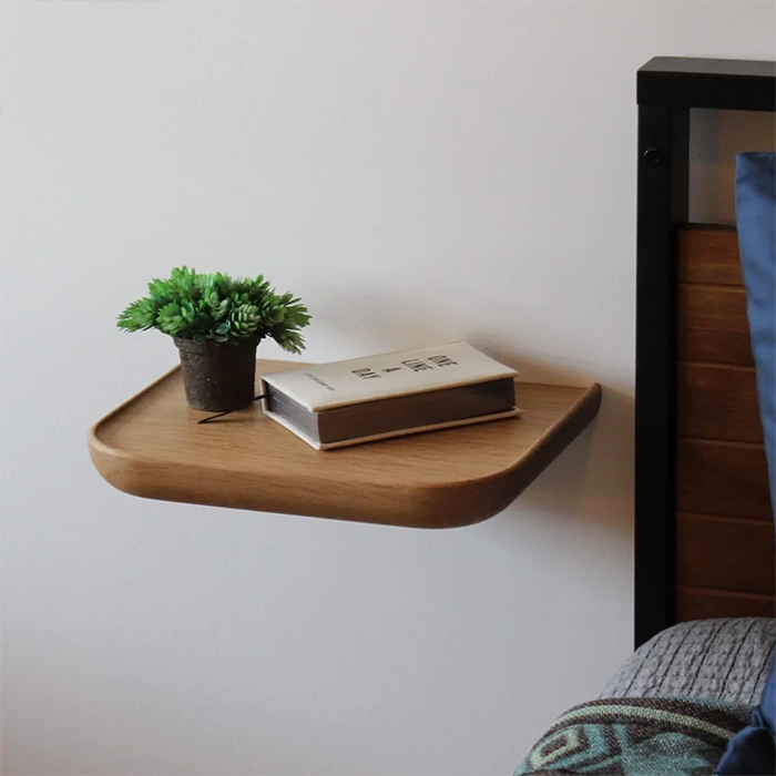 Minimalist floating nightstand with a book and plant on it.