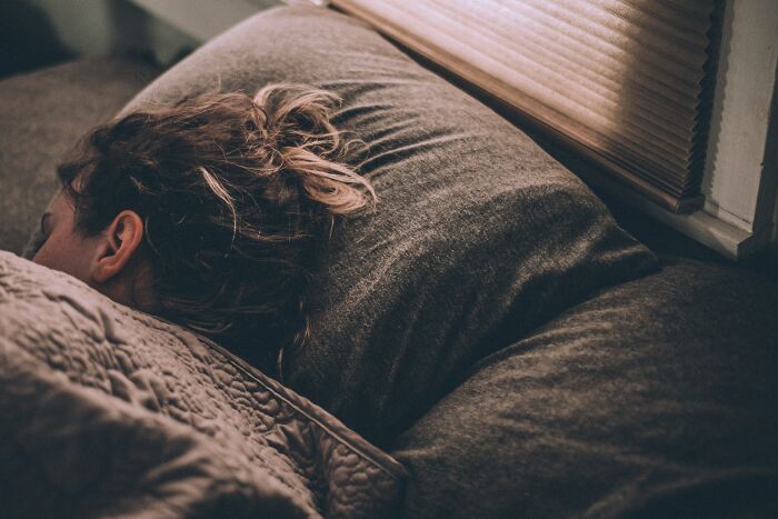 Woman sleeping in dark gray bed