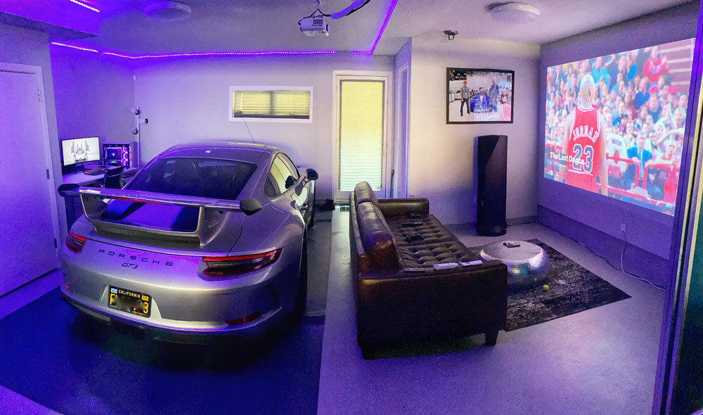 Silver Porsche GT3 parked inside a stylish game room with projector screen watching basketball in a modern gaming cave. Silver Porsche GT3 parked inside a stylish game room with projector screen watching basketball in a modern gaming cave.