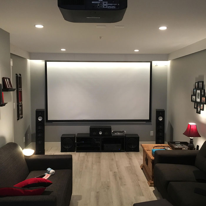 Bright game room with home theater projector, surround sound speakers, and cozy seating in a modern gaming cave setup. Bright game room with home theater projector, surround sound speakers, and cozy seating in a modern gaming cave setup.