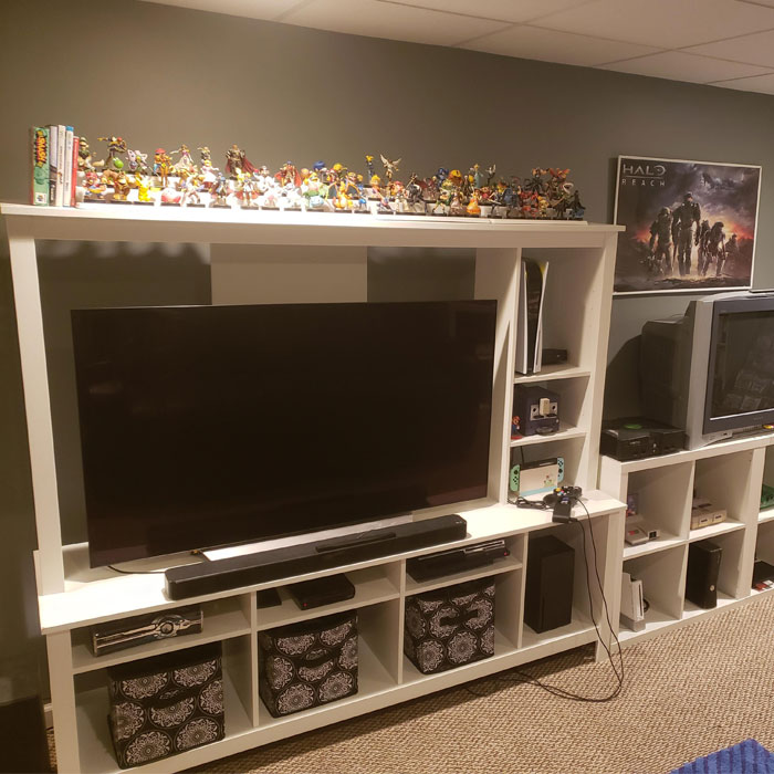 Game room with additional storage space featuring a large TV, gaming consoles, and collectible figures display. Game room with additional storage space featuring a large TV, gaming consoles, and collectible figures display.