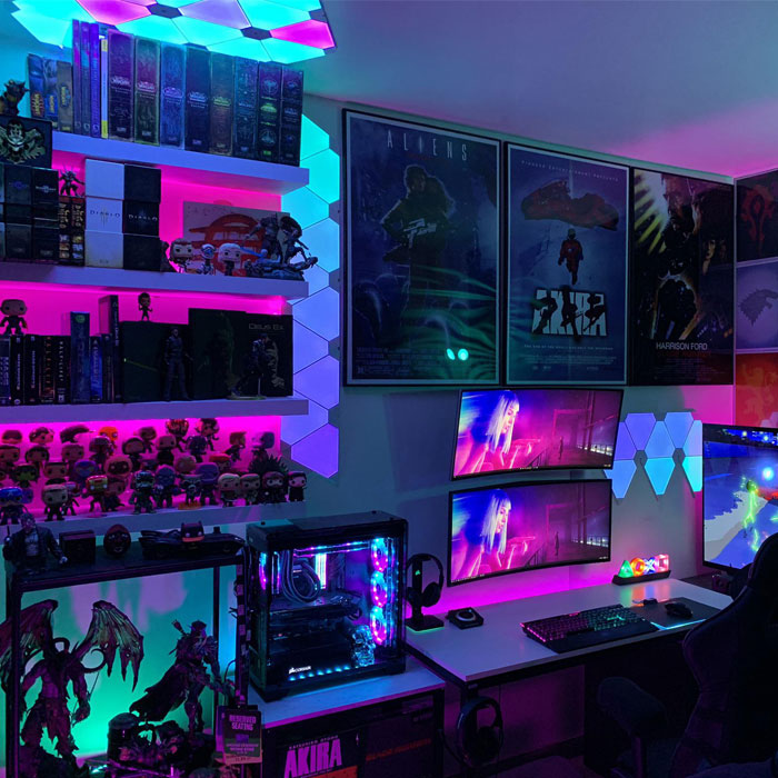 Game room with neon sign accents, dual monitors, colorful LED lighting, and gaming collectibles on shelves. Game room with neon sign accents, dual monitors, colorful LED lighting, and gaming collectibles on shelves.