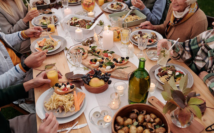 Family dinner gathering with multiple generations sharing food and drinks in a lively outdoor setting Family dinner gathering with multiple generations sharing food and drinks in a lively outdoor setting
