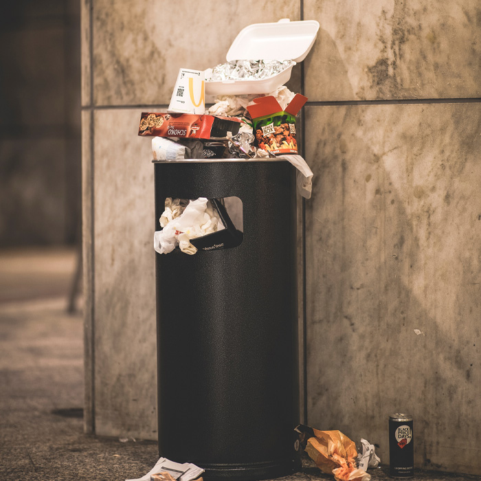Black garbage can with trash in it 
