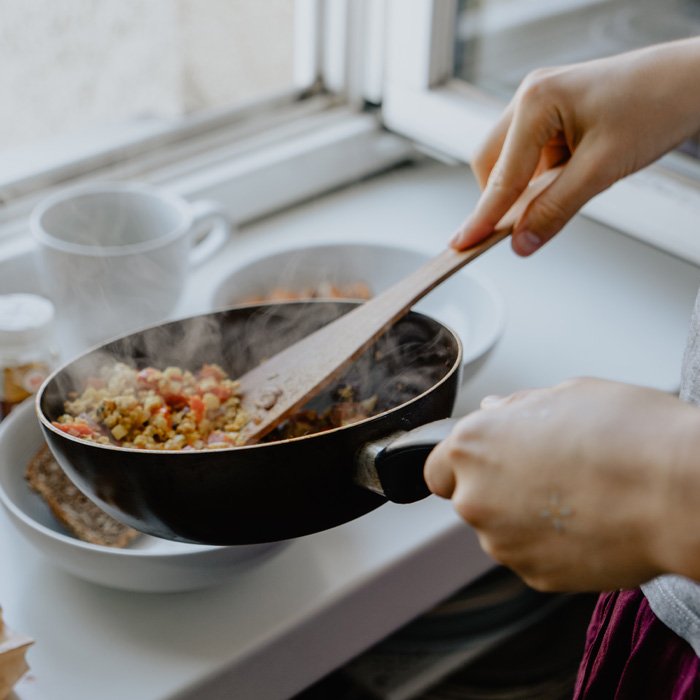 Person holding a pan and cooking 