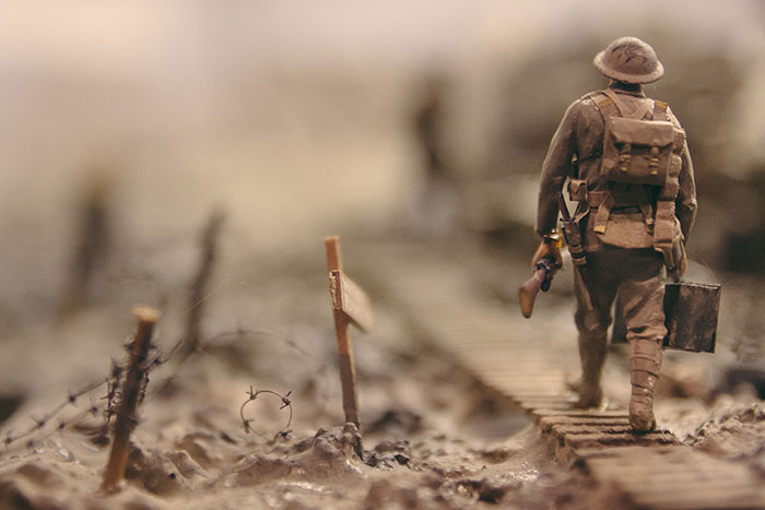 Soldier walking on wooden pathway surrounded with barbed wire