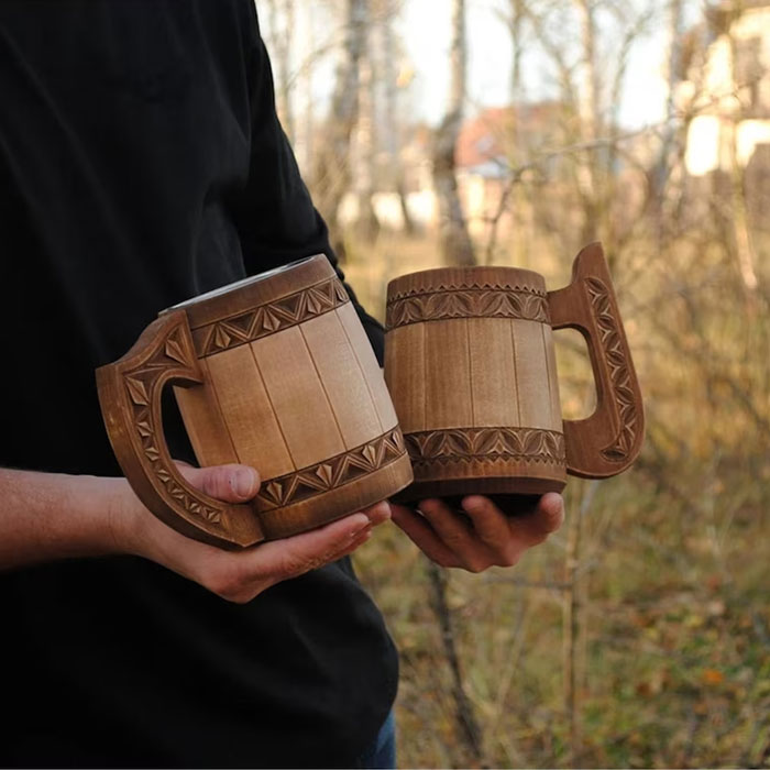 Person holding two wooden mugs in his hands