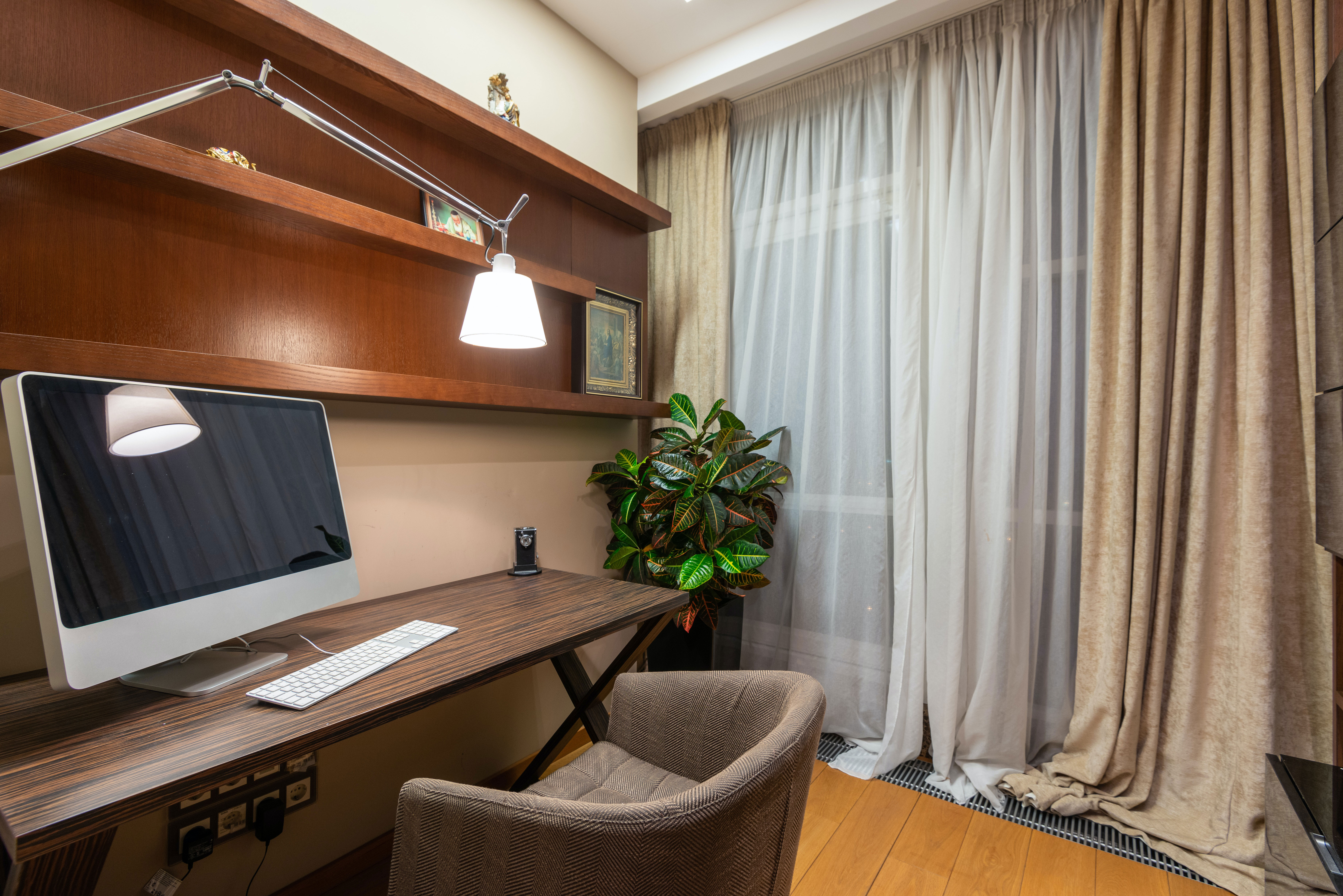 Modern home office setup with a comfortable chair, wooden desk, monitor, and natural light for productive work ideas Modern home office setup with a comfortable chair, wooden desk, monitor, and natural light for productive work ideas