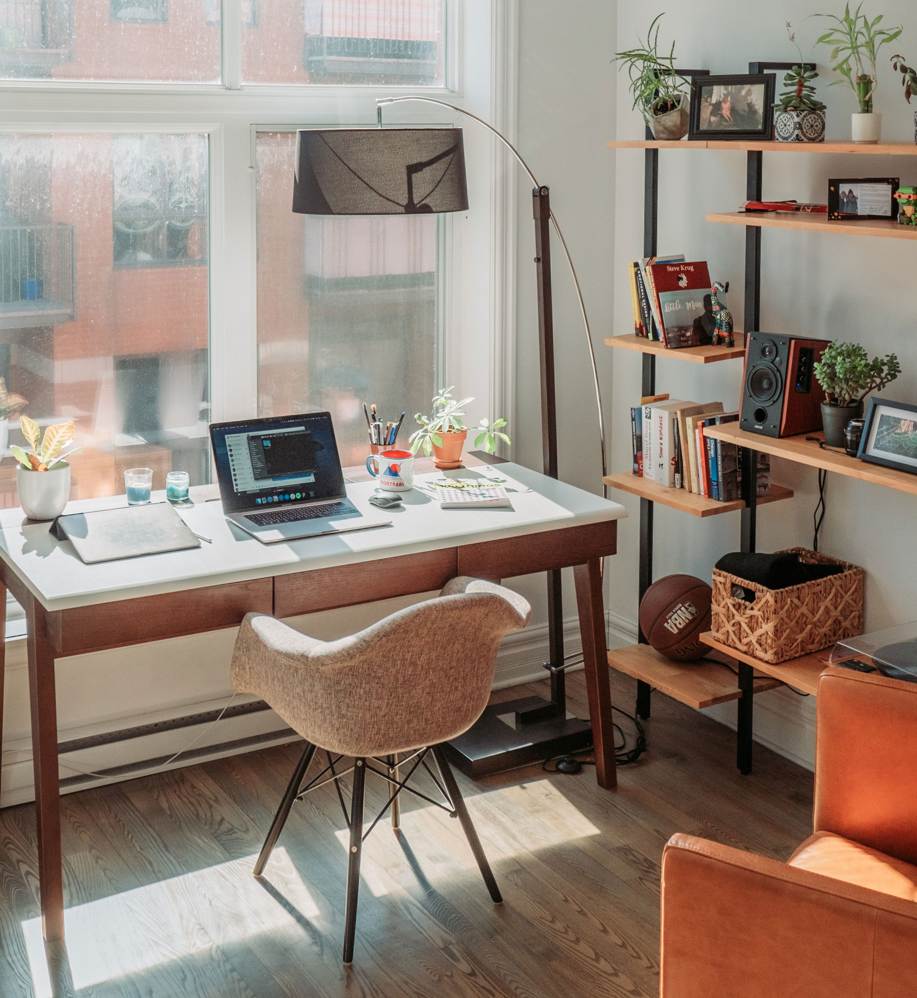 Bright home office with black laptop on wooden table, modern chair, plants, and shelves for an inspired and productive work process Bright home office with black laptop on wooden table, modern chair, plants, and shelves for an inspired and productive work process