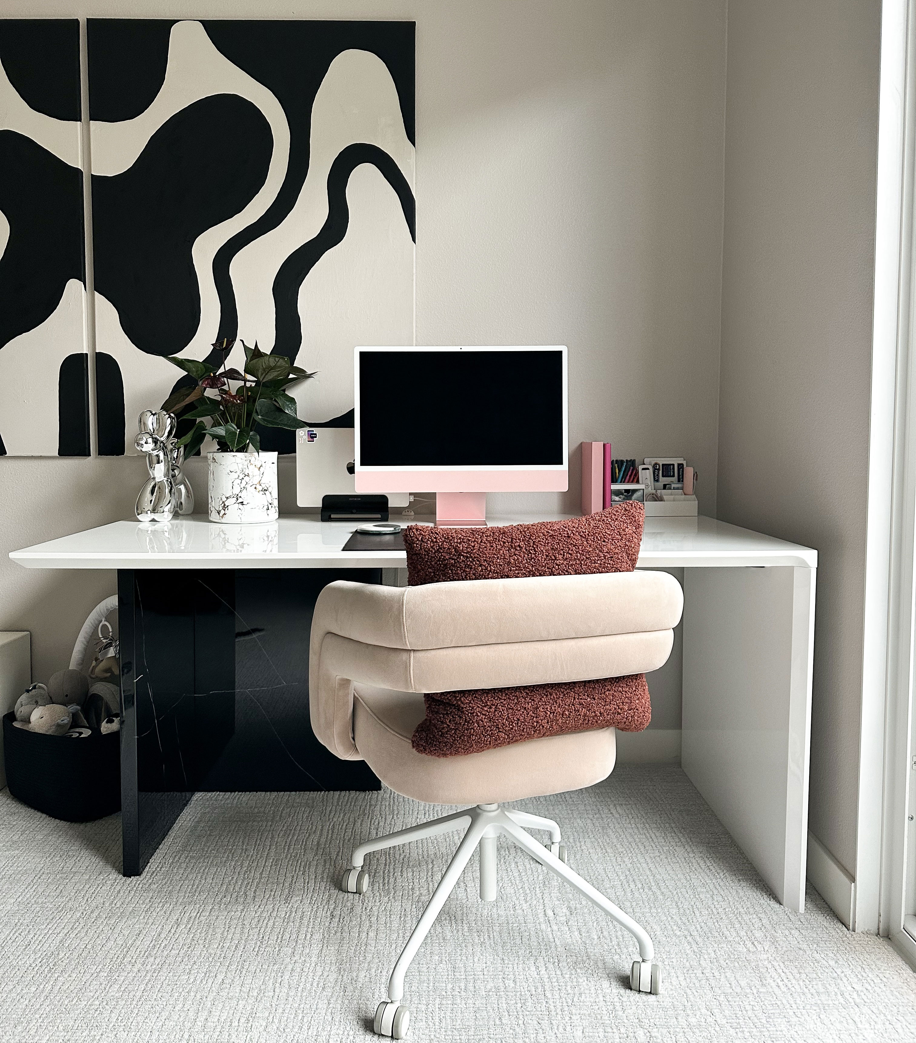 Minimalist home office setup with large-scale abstract art, pink computer, and comfortable swivel chair for productivity. Minimalist home office setup with large-scale abstract art, pink computer, and comfortable swivel chair for productivity.
