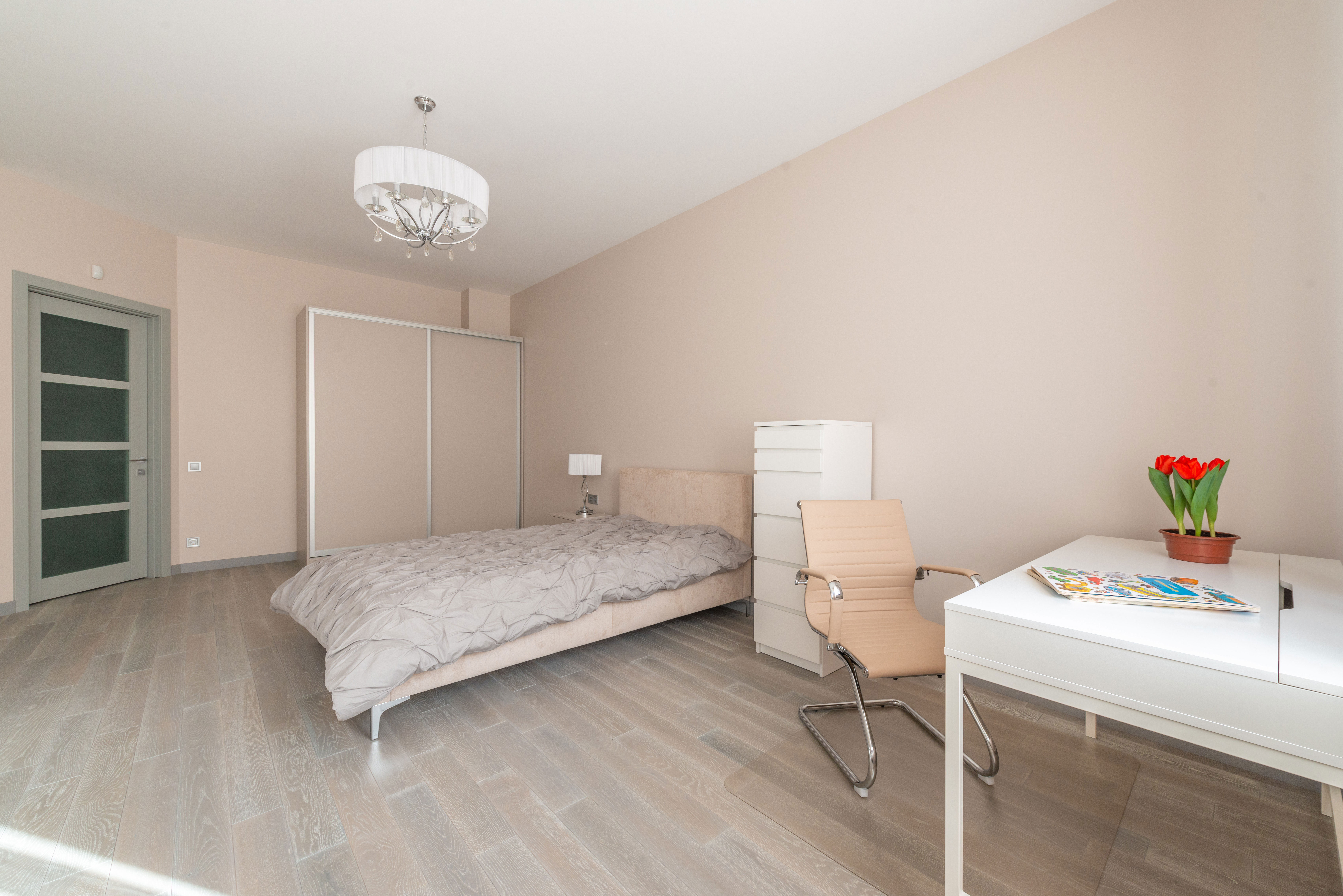 Beige bedroom with bed and a home office setup featuring a white desk and beige chair for a productive work process. Beige bedroom with bed and a home office setup featuring a white desk and beige chair for a productive work process.