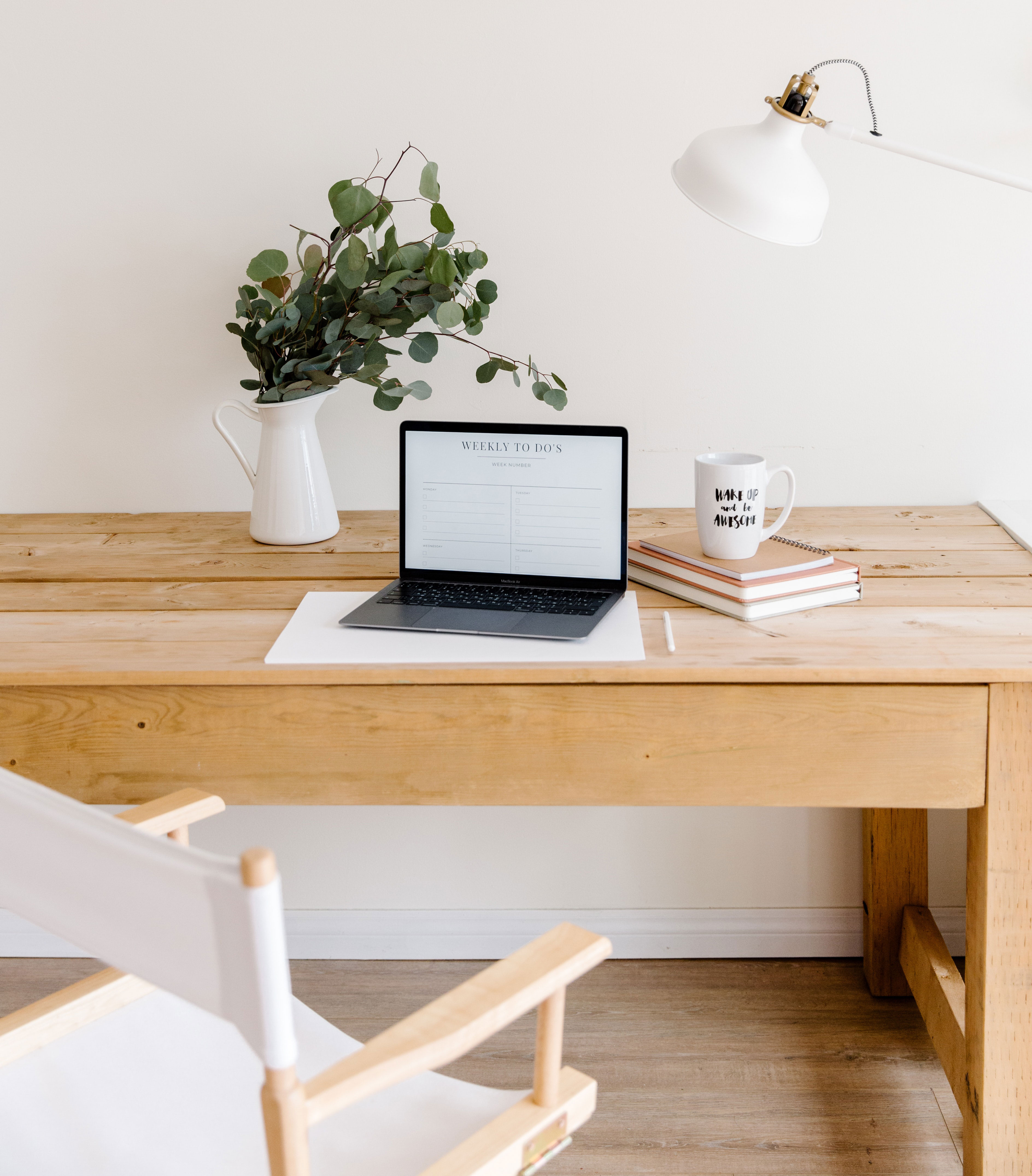 Minimalist home office setup with wooden desk, laptop, plant in vase, white chair, and task lamp for productive workspace ideas Minimalist home office setup with wooden desk, laptop, plant in vase, white chair, and task lamp for productive workspace ideas