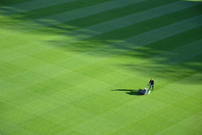 Man cutting grass with lawn mower in golf field