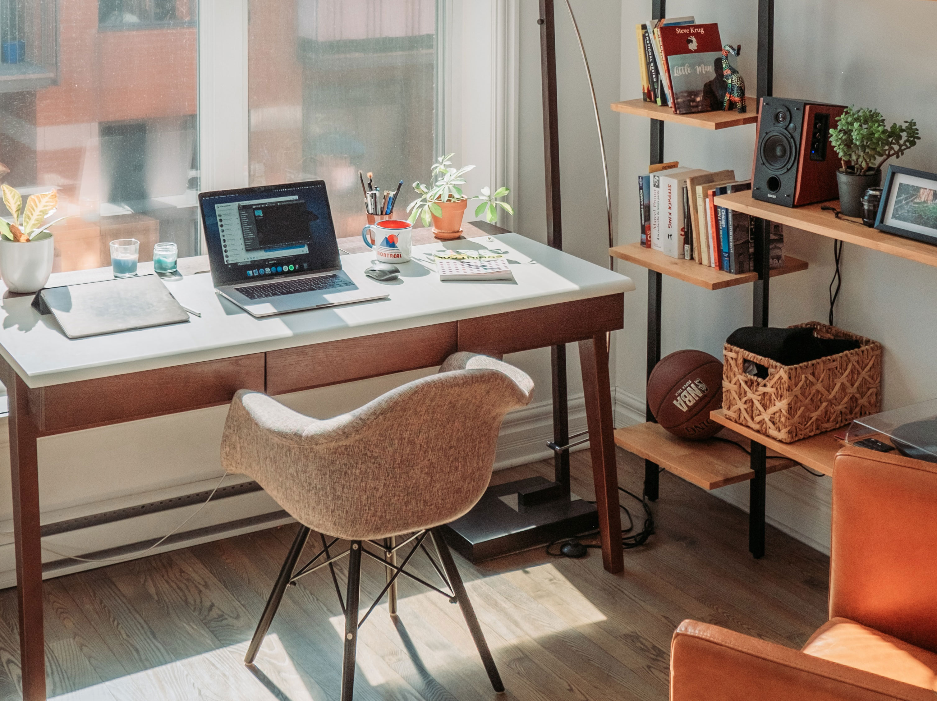 wooden table near window and wooden bookshelf