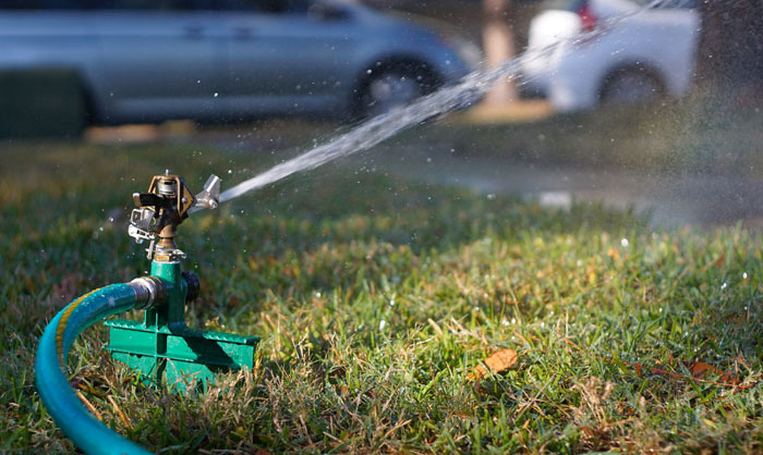 A sprinkler is spraying water on a lawn A sprinkler is spraying water on a lawn