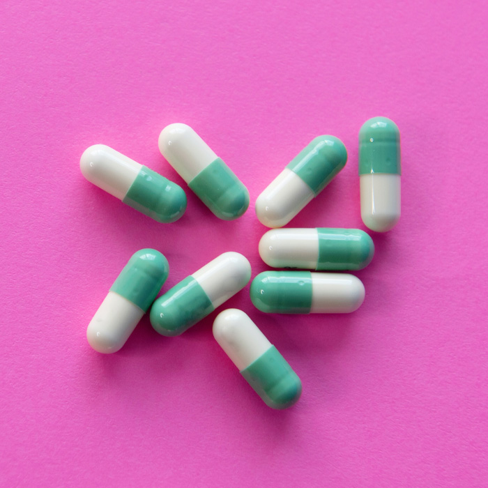 White and blue pills on the pink background 