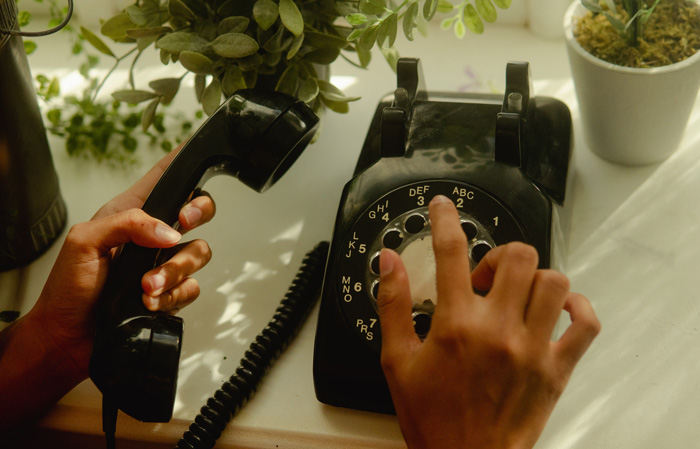A person dialling phone number on an old phone 