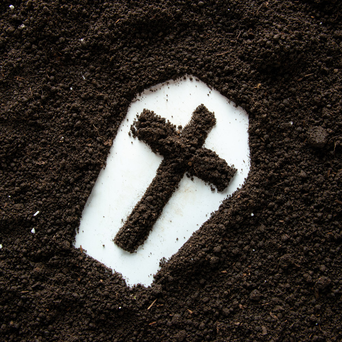 A coffin shape with cross and brown soil