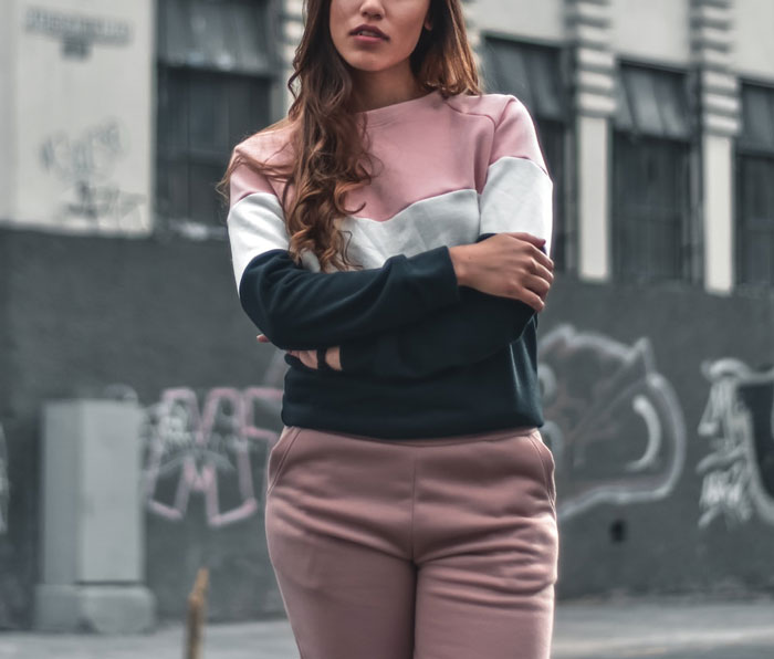 Young woman standing outdoors with arms crossed, reflecting a family intervention moment related to a man visiting mom. Young woman standing outdoors with arms crossed, reflecting a family intervention moment related to a man visiting mom.
