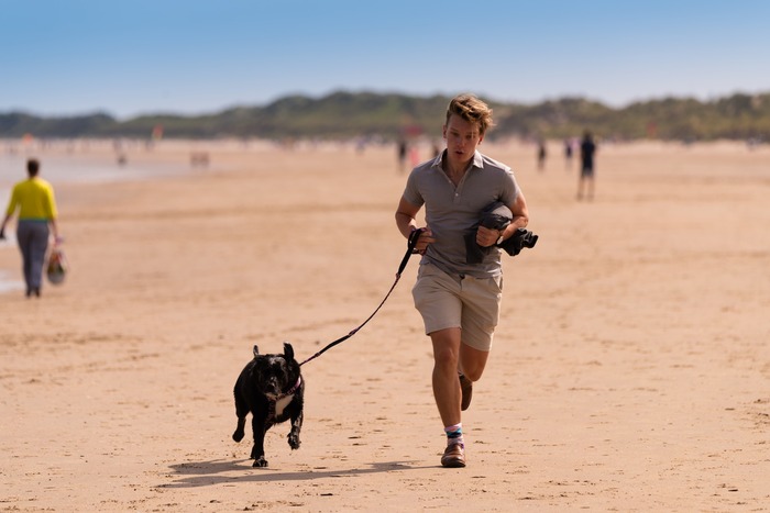 man is running with his dog on the beach