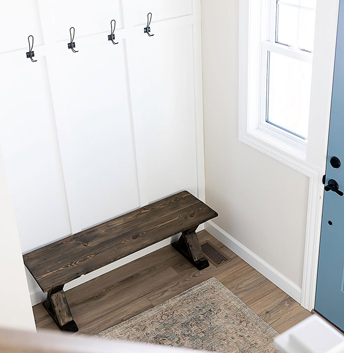 Ebony wood stain on a bench in a bright anteroom with white walls, hooks, and natural light from a window. Ebony wood stain on a bench in a bright anteroom with white walls, hooks, and natural light from a window.