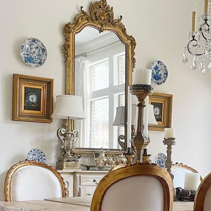 Golden framed mirror on wall reflecting window, featuring old money interior design elements with elegant decor and classic furniture. Golden framed mirror on wall reflecting window, featuring old money interior design elements with elegant decor and classic furniture.