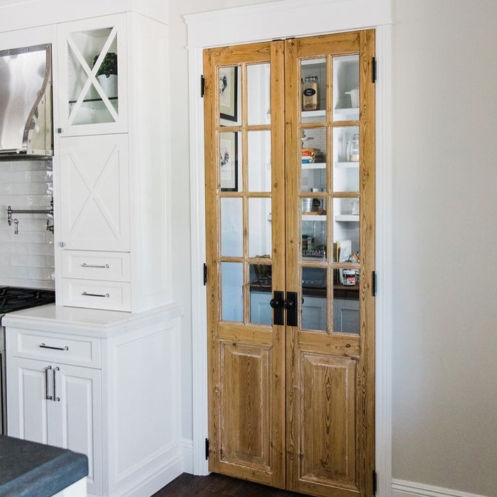 Wooden pantry door in the white kitchen 
