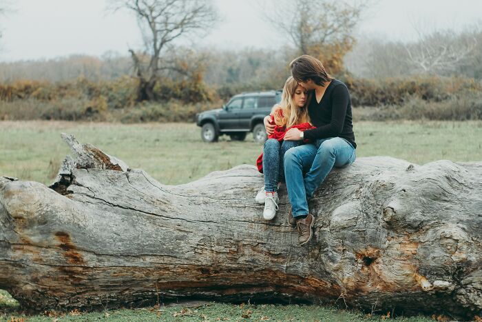 Man and woman hugging on while on a tree log