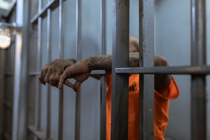A Person in Orange Shirt with Tattooed Arms in prison 