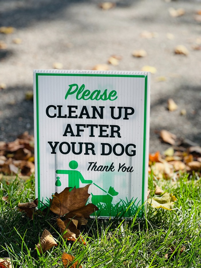 Sign on grass reading "Please clean up after your dog," promoting ways to keep dogs from pooping in your yard. Sign on grass reading "Please clean up after your dog," promoting ways to keep dogs from pooping in your yard.