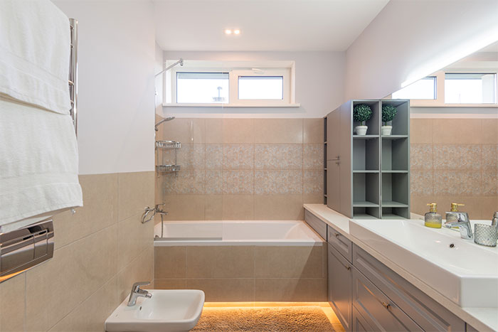 shot of a bathroom with beige tiles and a yellow lit carpet