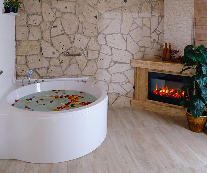 Romantic bathtub with flowers near fireplace