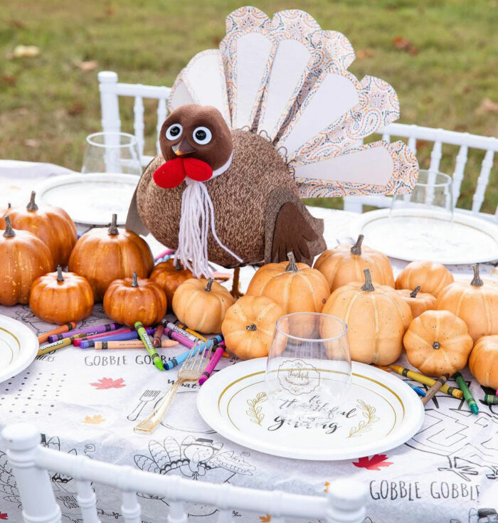 Toy-turkey with pumpkins in the center of dining table