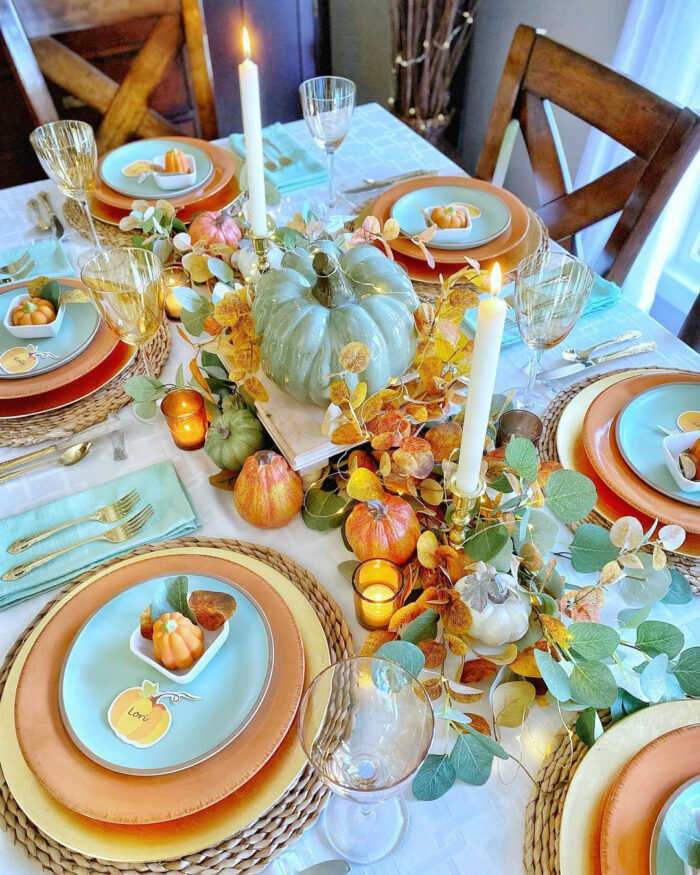 Big turquoise pumpkin with orange leaves in center of table