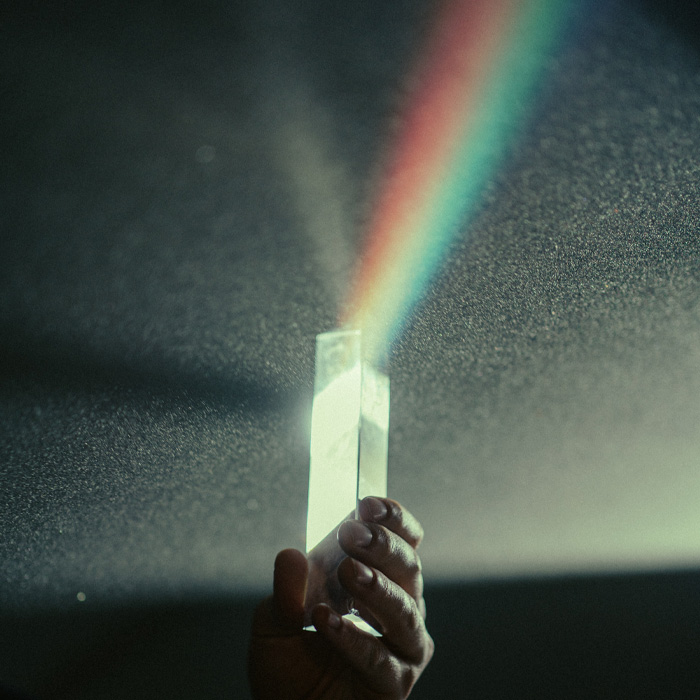 Person holding a prism with rainbow light 