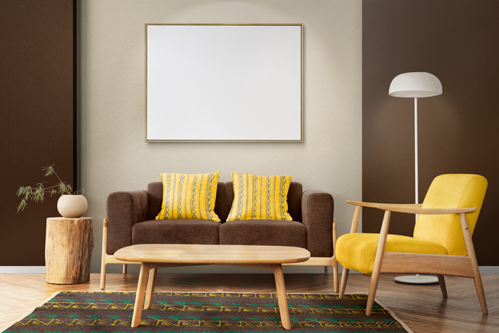 A brown couch with yellow pillows next to a yellow chair 