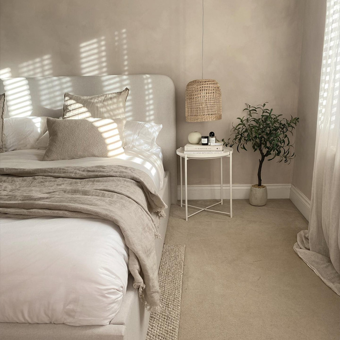 Bedroom with a grey bed and nightstand featuring warm color decor and soft natural lighting for cozy ambiance Bedroom with a grey bed and nightstand featuring warm color decor and soft natural lighting for cozy ambiance