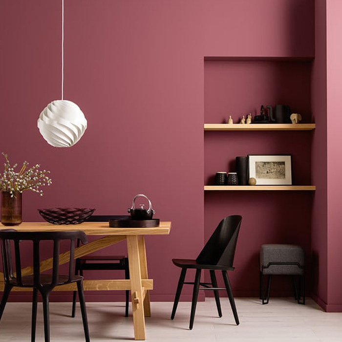 Burgundy dining room featuring warm colors with a wooden table, black chairs, and minimalist decor on shelves. Burgundy dining room featuring warm colors with a wooden table, black chairs, and minimalist decor on shelves.