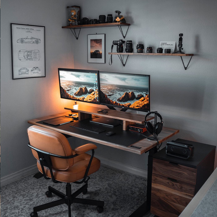 Home office with wooden desk with the monitors on it and brown leather chair