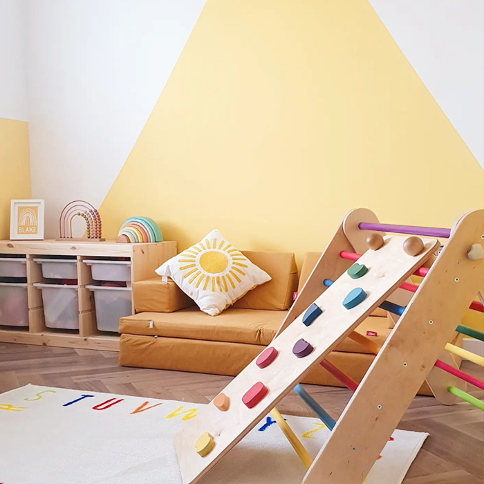 Yellow kid's playroom featuring warm colors with an orange couch, sun-themed pillow, and colorful climbing toy. Yellow kid's playroom featuring warm colors with an orange couch, sun-themed pillow, and colorful climbing toy.