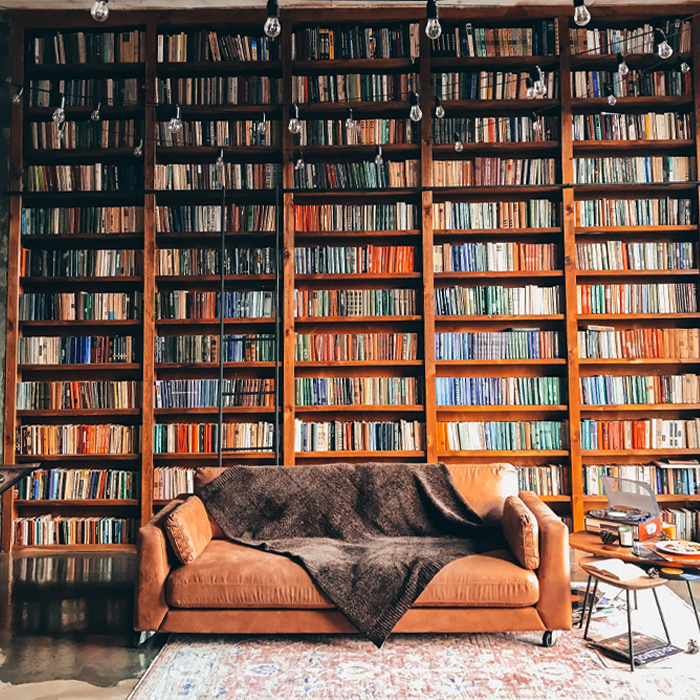 Brown wooden book shelves next to a brown leather couch 